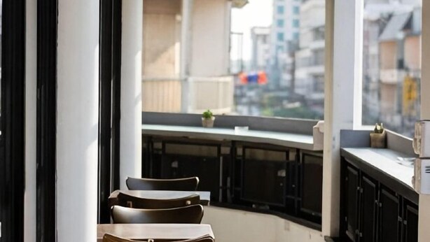 A balcony with chairs and a table, overlooking a cityscape. - Anou Hotel (Vientiane)