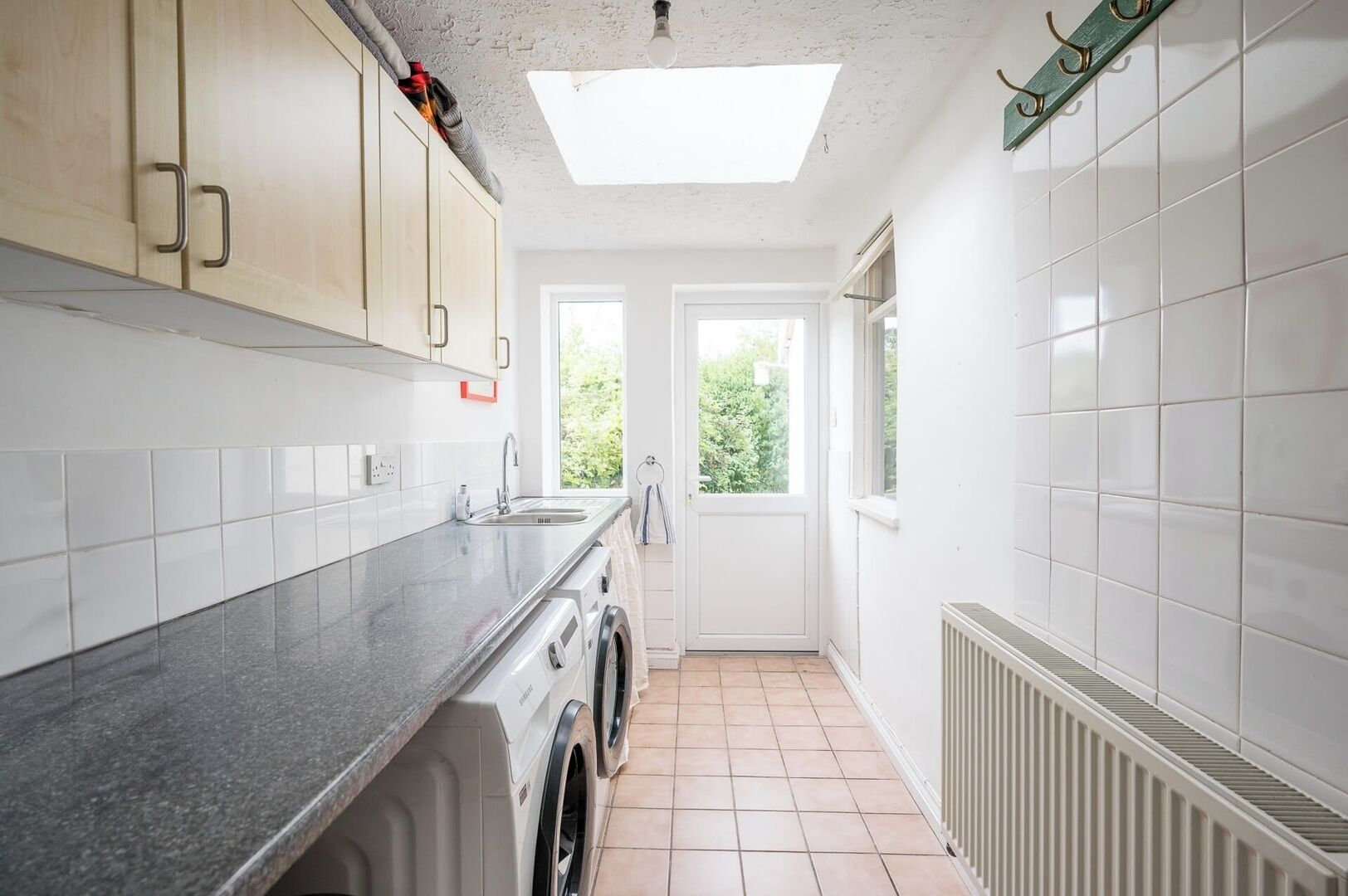 A kitchen with a washing machine, a sink, and a window.