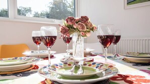 A dining table with plates, glasses, and a vase of flowers.