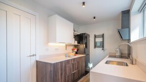 A modern kitchen with white cabinetry, a built-in oven, and a stainless steel sink. - 1 Leiston Court, Leiston (Leiston)