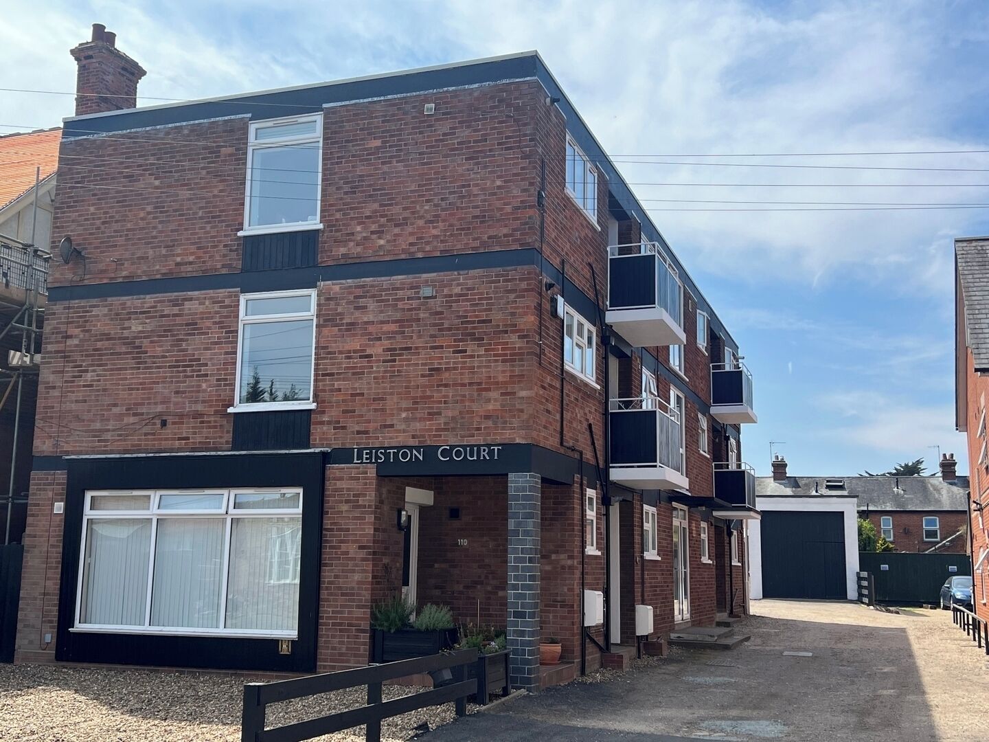 A multi-story brick building with a sign reading 'Leiston Court.'