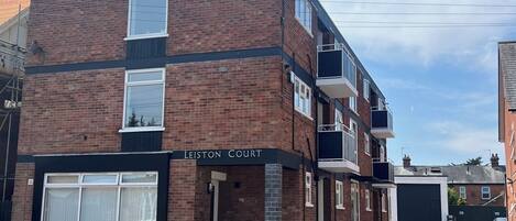 A multi-story brick building with a sign reading 'Leiston Court.'