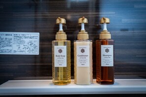 Trois bouteilles de savon pour le corps, d’après-shampoing et de shampoing sont posées sur une étagère.