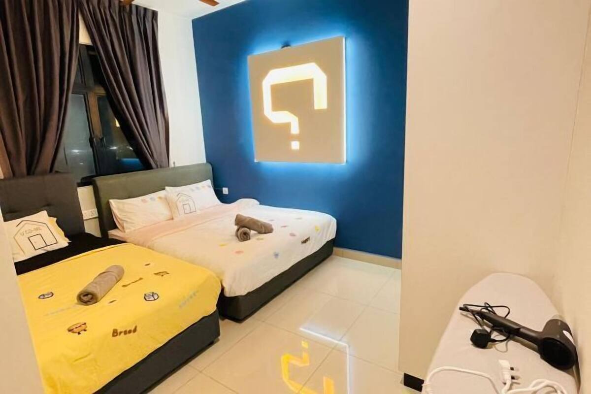 A hotel room with a bed, a desk, and a wall-mounted light fixture.