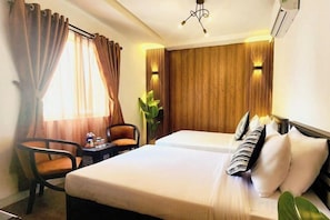A hotel room with a bed, two chairs, a small table, and a potted plant. - RosaMay Thu Khoa Huan (Ho Chi Minh City)