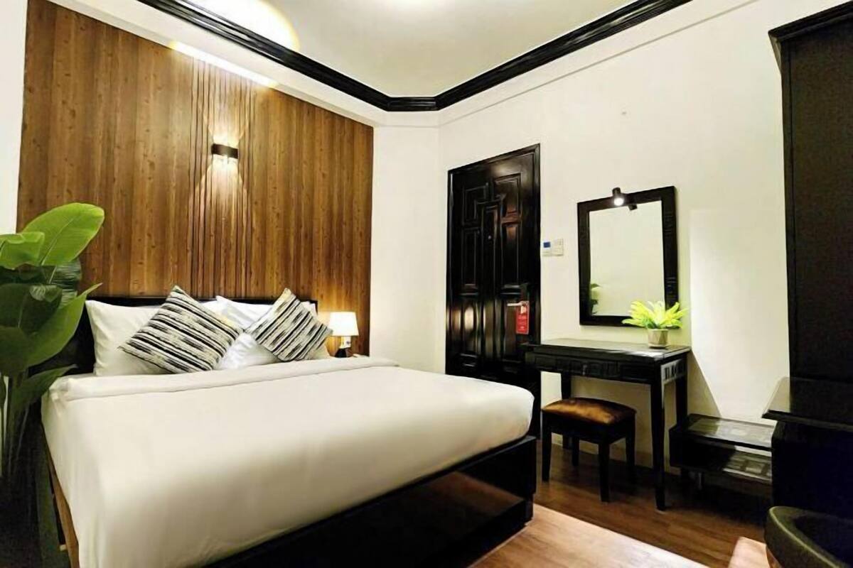 Une chambre d’hôtel équipée d’un lit, d’un bureau, d’une chaise et d’un miroir.