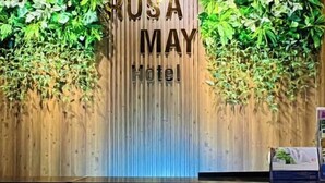 A reception desk with a wooden backdrop and green foliage. - RosaMay Thu Khoa Huan (Ho Chi Minh City)