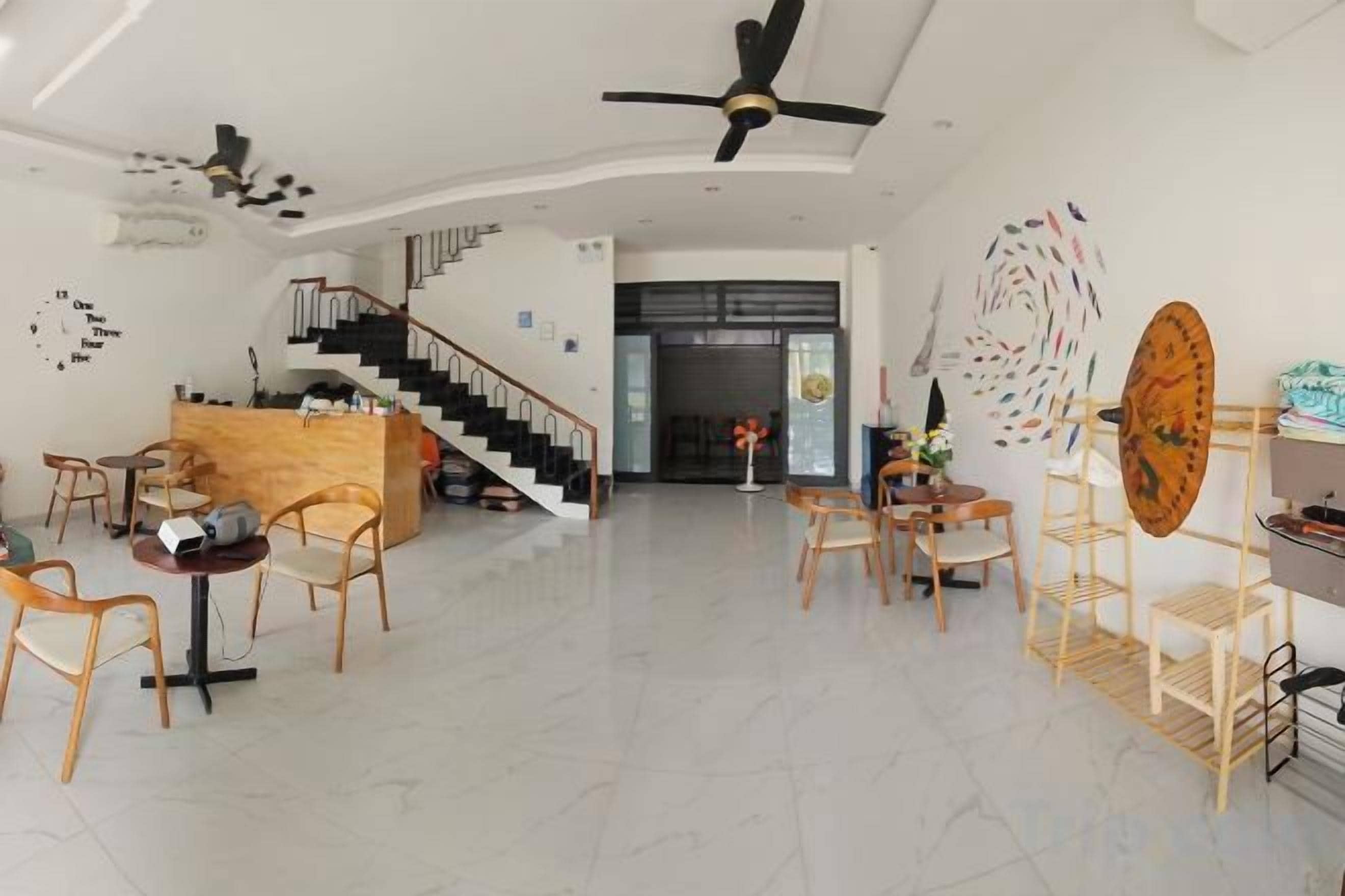 Un amplio vestíbulo de hotel con una escalera central, una recepción y varias zonas de estar.