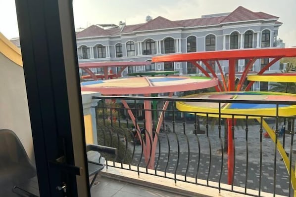 Un balcón con vista a un parque infantil y un edificio con ventanas de arco.