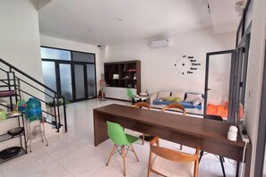 A modern living room with a dining area, a staircase, and a large window. - ADRi (Phu Quoc Island)