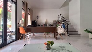 Un intérieur moderne comprenant un coin repas, un escalier et une vue dégagée grâce à de grandes fenêtres.