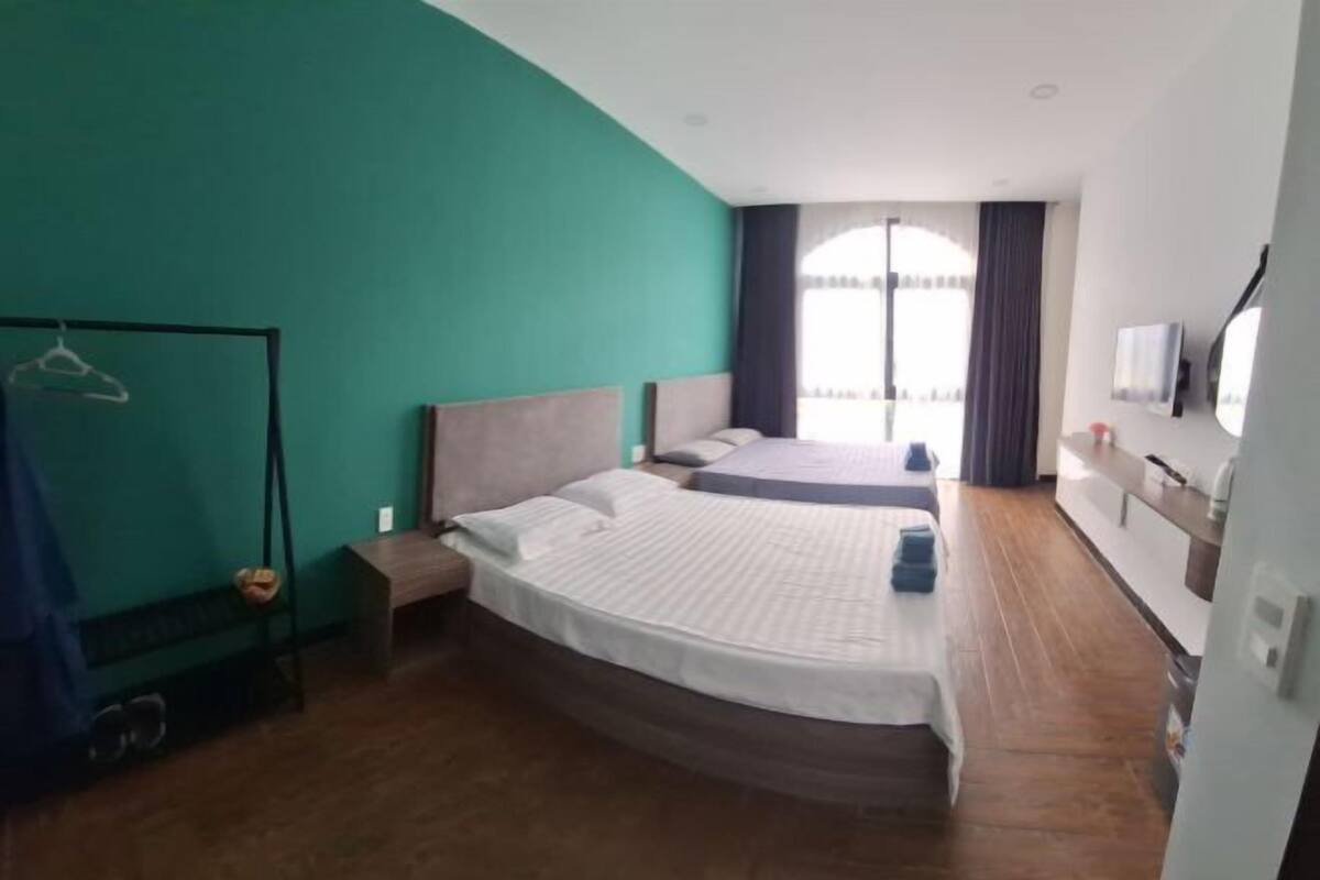 A hotel room with a curved bed, a TV, a wardrobe, and a view of the outdoors.