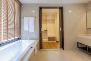 A modern bathroom with a bathtub, a walk-in shower, and a vanity with a mirror.