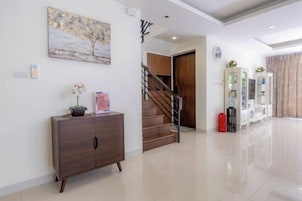 Un interior moderno con una escalera de madera, un mueble con una planta en maceta y un cuadro en la pared.