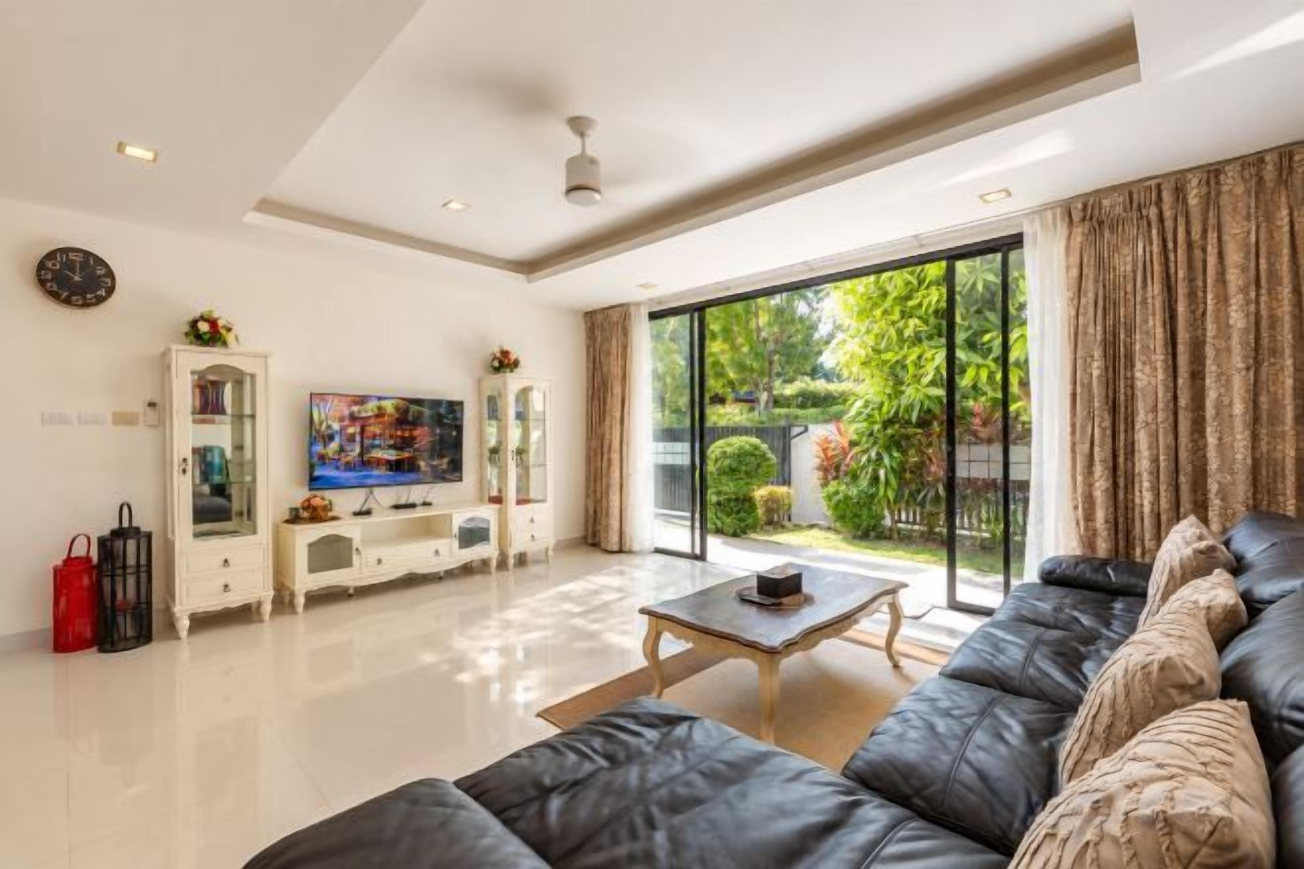 Un salon moderne comprenant un canapé, une table basse, un téléviseur et une porte-fenêtre coulissante donnant sur un jardin.