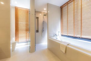 Un baño moderno con bañera, ducha y persianas de madera.