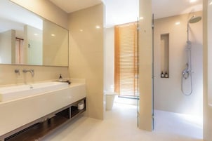 Un baño moderno con un espejo grande, lavamanos doble, ducha e inodoro.