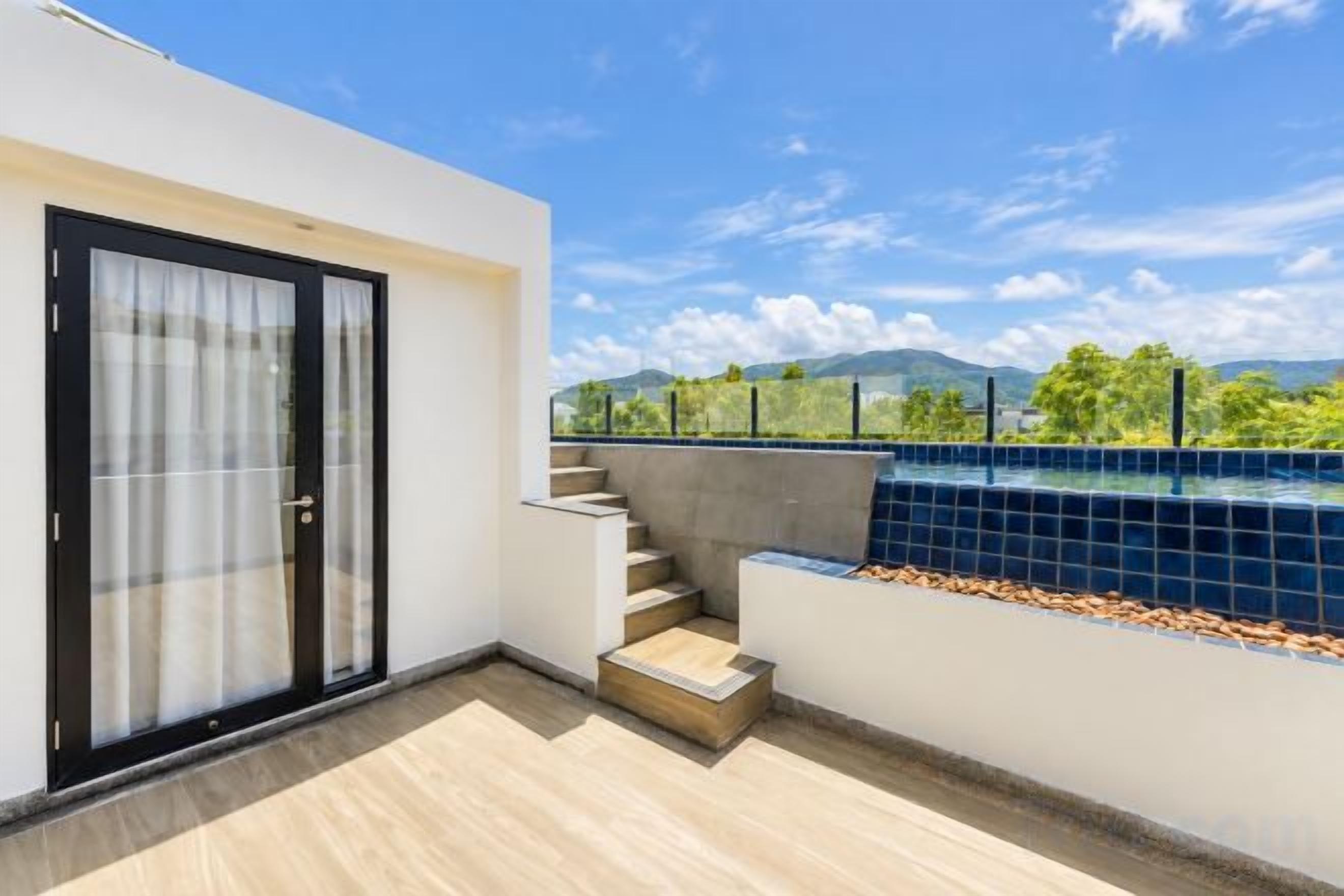 Ein moderner Balkon mit Pool, Treppe und Blick auf Grünflächen und Berge.