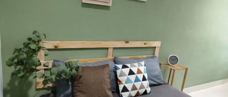 A bed with a wooden headboard, multiple pillows, and a bedside plant.