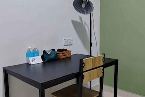 Una pequeña mesa con un ventilador, una botella de agua, un bolso y una caja.