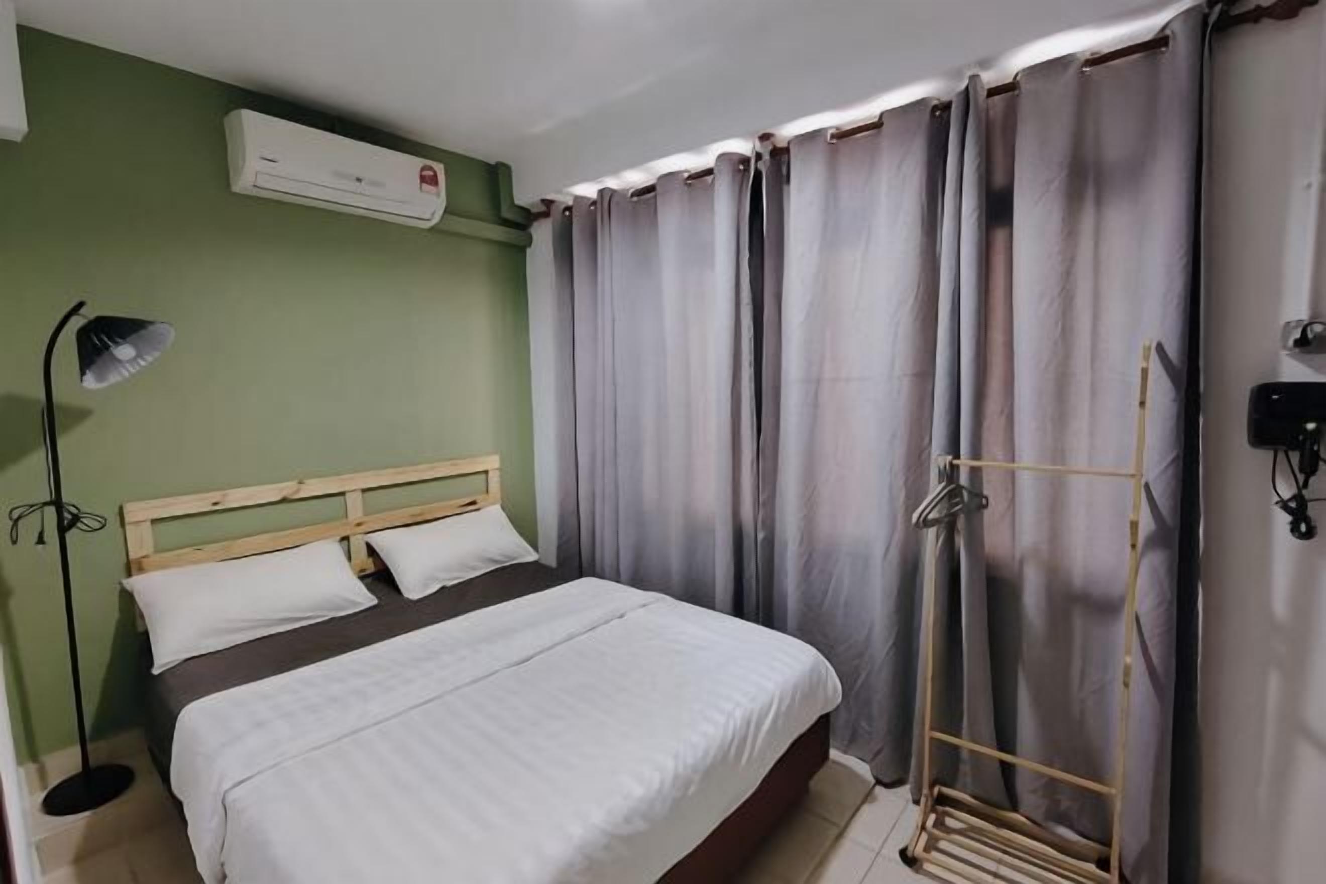 A bedroom with a bed, a bedside lamp, a curtain, and an air conditioning unit.