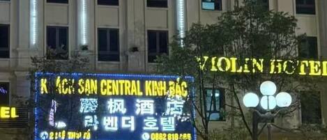 Un edificio con señalización iluminada que dice 'KICHEN CENTRAL KINHBAO' y 'VIOLIN HOTEL'.