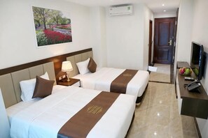Habitación de hotel con dos camas, televisor, escritorio y un cuadro en la pared.