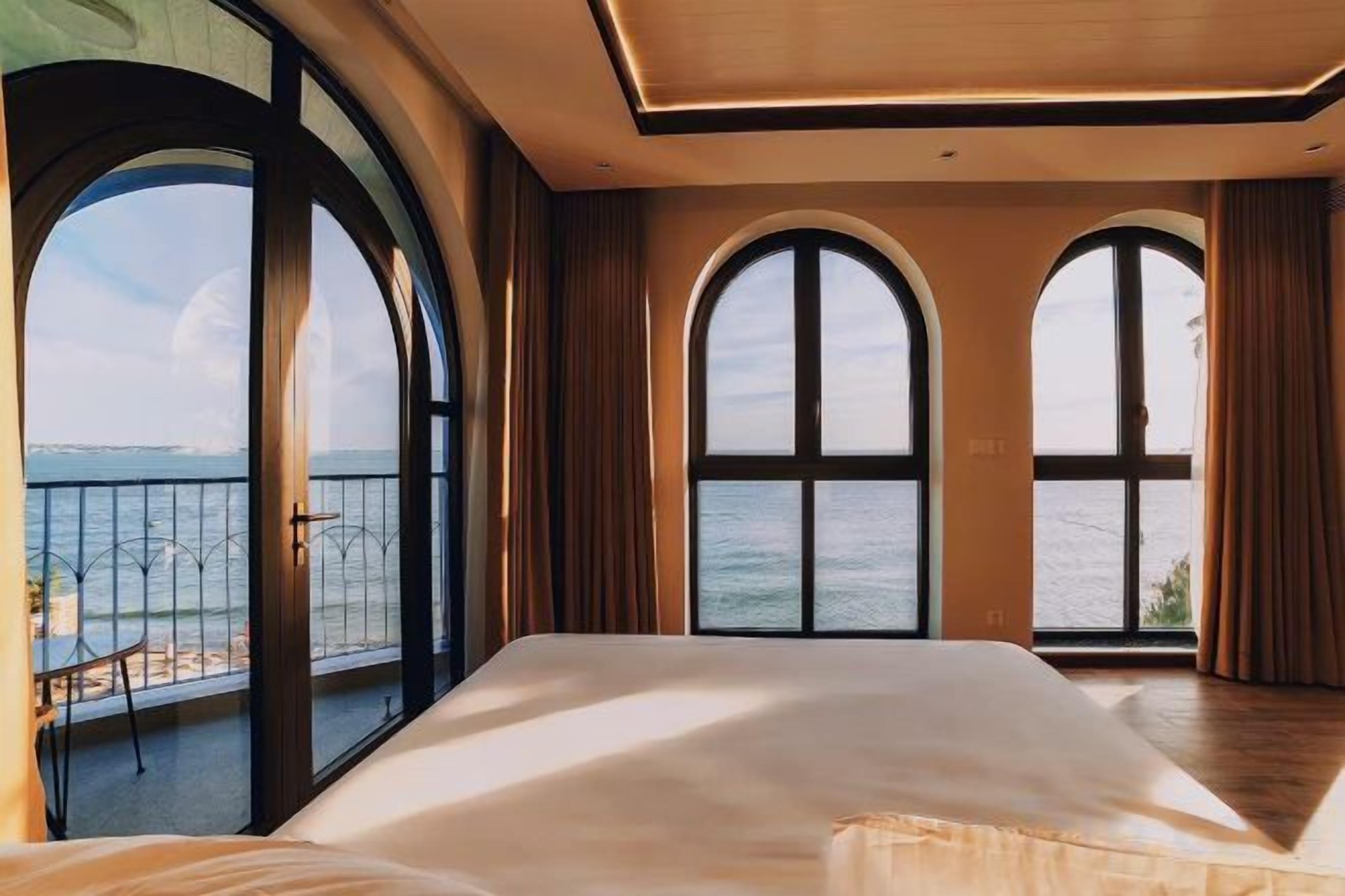 Un dormitorio con una cama grande, ventanas en arco y vista al mar.