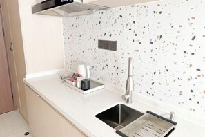 Cozinha com bancada branca, pia de aço inoxidável e painel de fundo com padrão pontilhado.