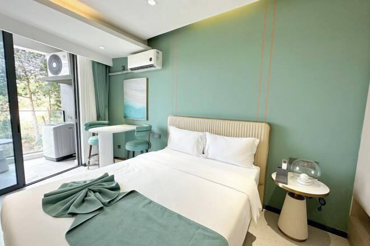 Een moderne hotelkamer met een bed, een tafeltje, een stoel en uitzicht op het omliggende landschap.