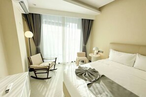 A hotel room with a bed, a chair, a small table, and a lamp. - Ark hotel Sihanoukville (Prey Nob)