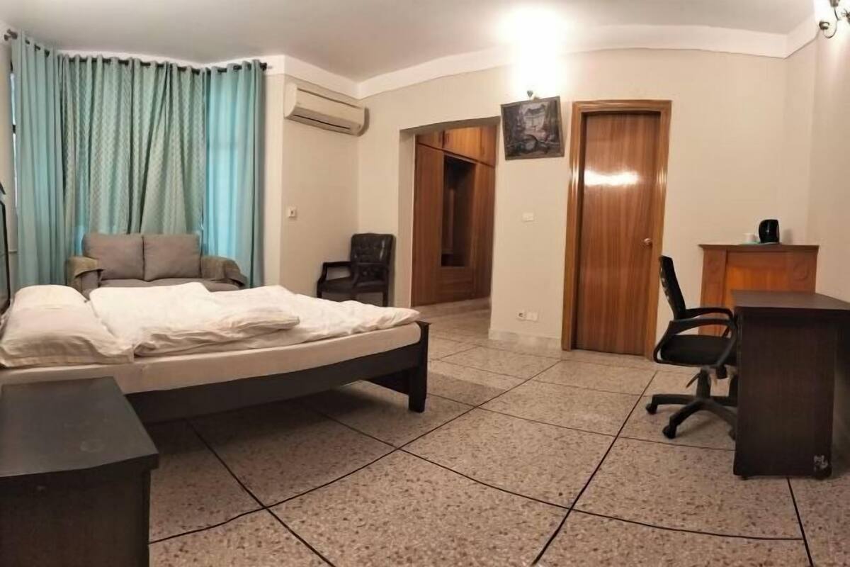 A bedroom with a bed, a desk, a chair, a wardrobe, and a door.