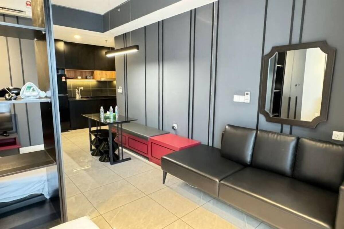 A modern living area with a sofa, a dining table, and a kitchen in the background.