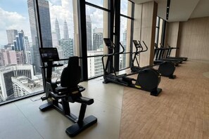 Un gimnasio con equipo de ejercicio y vistas a la ciudad.