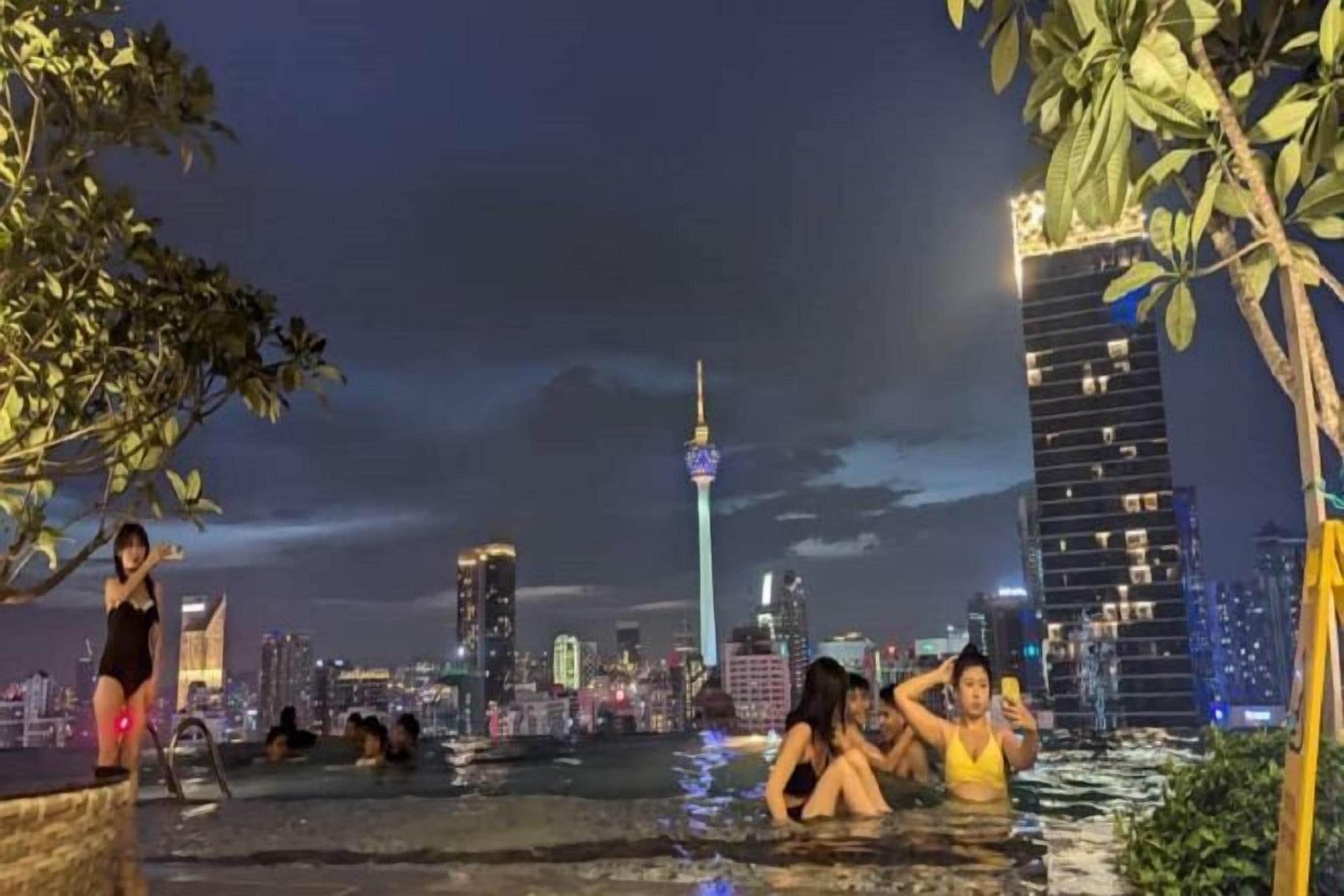 An outdoor swimming pool area with a city skyline in the background, including a prominent tower.