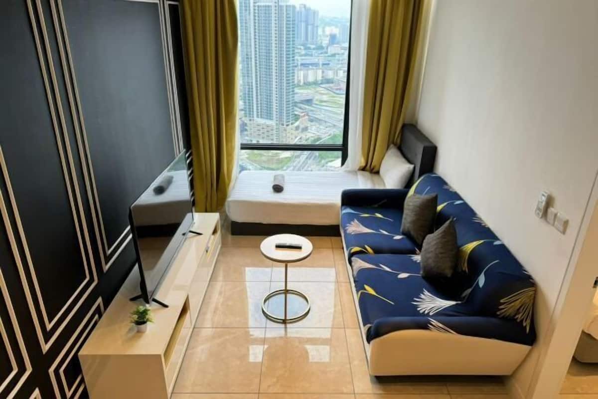 A modern living room with a sofa, a small round table, a TV, and a window with curtains.