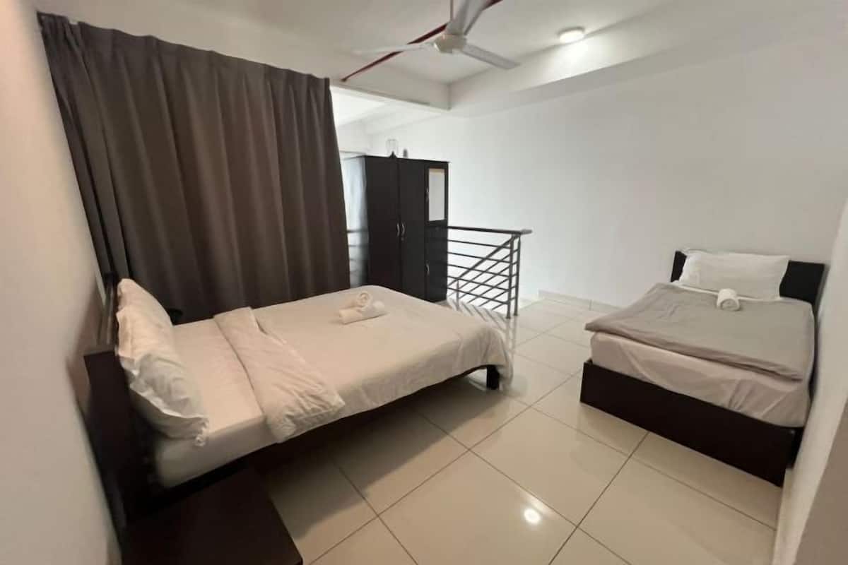 Une chambre avec deux lits, une armoire, un ventilateur de plafond et un escalier menant à un étage supérieur.
