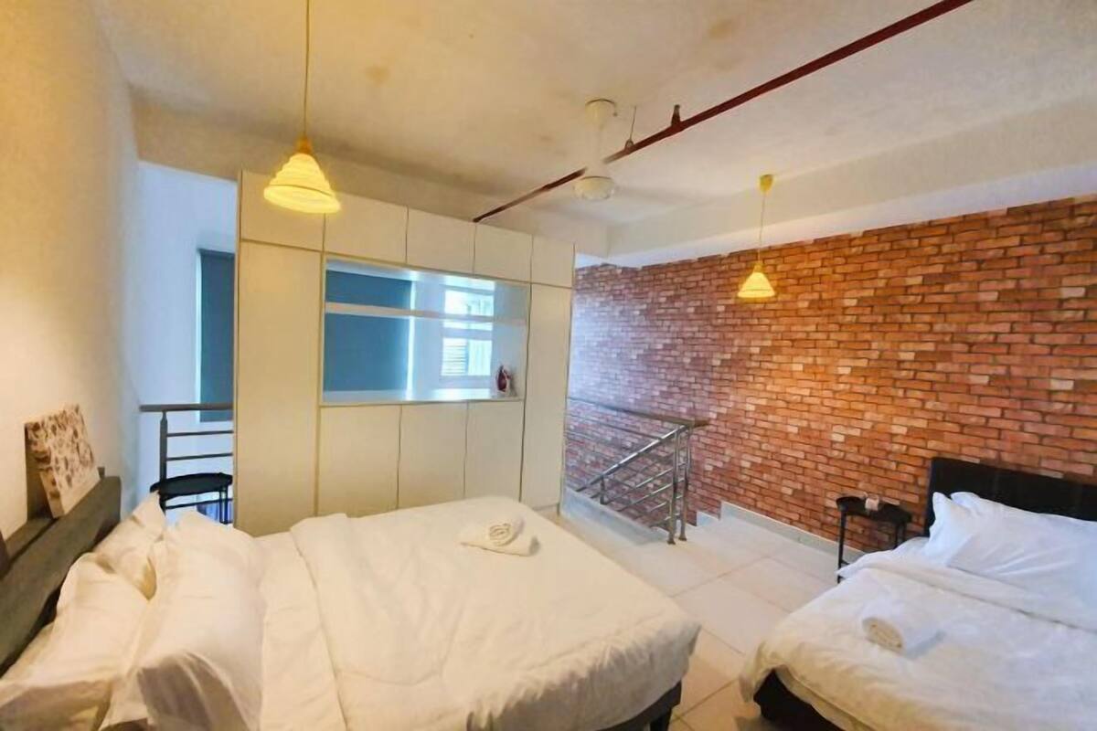 Une chambre d’hôtel avec deux lits, un mur en briques, un balcon et une fenêtre.