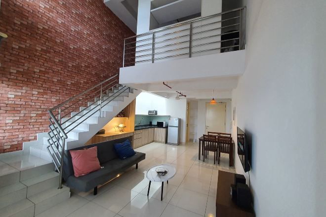 A spacious living area with a staircase, a sofa, a coffee table, and a dining area.