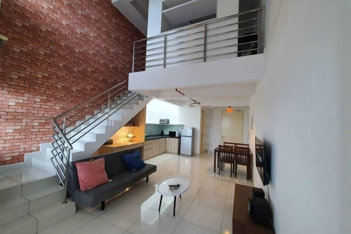 A spacious living area with a staircase, a sofa, a coffee table, and a dining area.