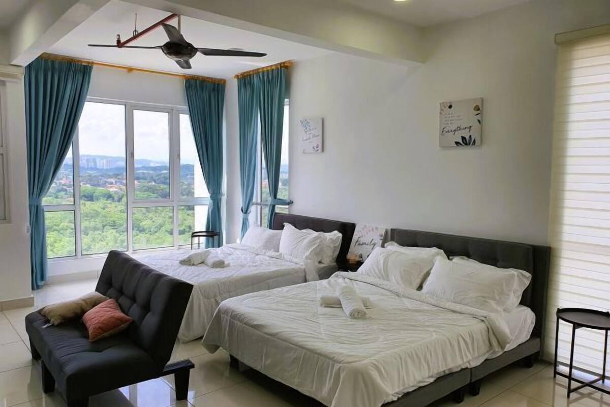 Une chambre d’hôtel avec deux lits, un canapé, un ventilateur de plafond et une vue sur la verdure environnante.