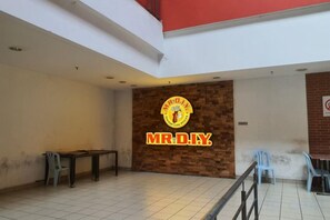 Een restaurantinterieur met een opvallend logo aan de muur, een zithoek met tafels en stoelen, en een betegelde vloer.