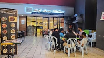 Un área de estar al aire libre de un restaurante con un tablero de menú a la izquierda.