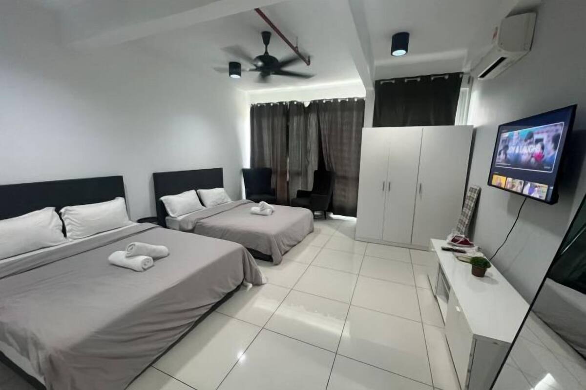 Une chambre d’hôtel avec deux lits, une télévision, une armoire et un ventilateur de plafond.