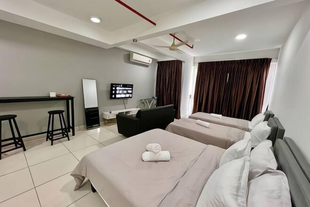 Une chambre d’hôtel avec deux lits, un bureau, une chaise, une télévision et un ventilateur de plafond.