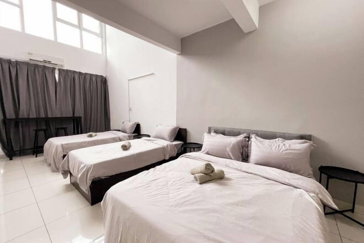 Une chambre d’hôtel avec trois lits, une grande fenêtre et un design moderne.