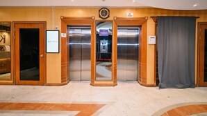 A lobby with two elevators, a clock, and a sign indicating a lift. - Kingston Hotel 6 @ Changkat Bukit Bintang (Kuala Lumpur)