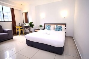 Una habitación de hotel con cama, escritorio, silla y sofá.