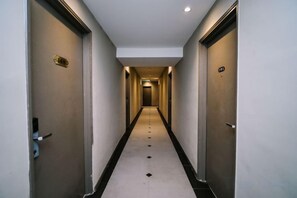Un lungo e stretto corridoio con porte su entrambi i lati, che conduce a un'area centrale.