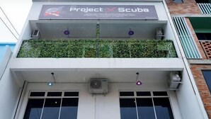 A building with a sign reading "Project Scuba" and a balcony with green plants. - Project X Scuba (Semporna)